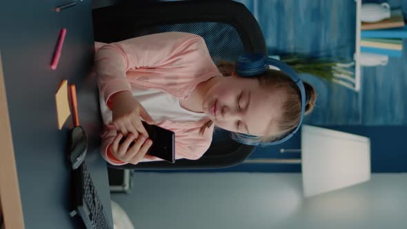 Vertical Video Little Girl Using Smartphone for Lessons on Video Call alt