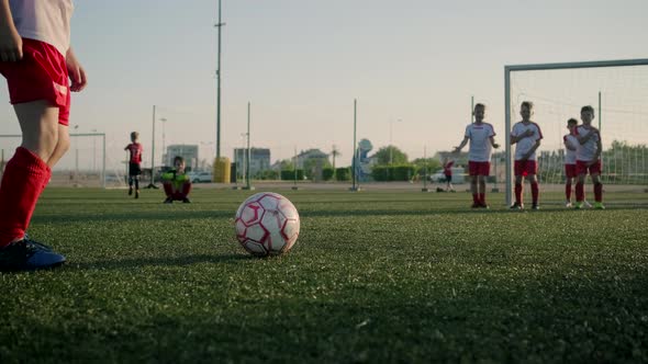çSchoolboy Junior League Player Kicks Ball Low Angle Shot alt
