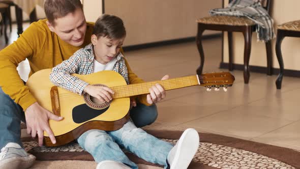 Man helping son to play guitar and singing son