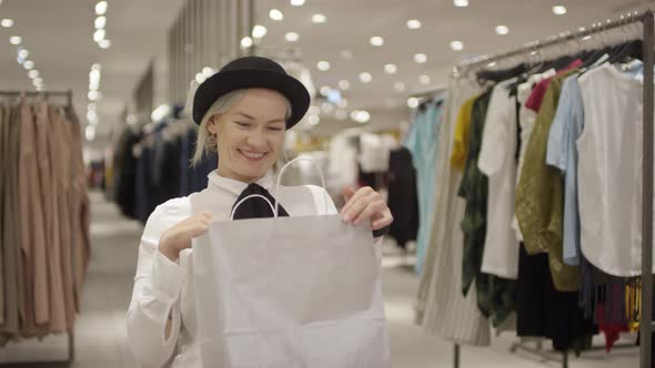 Young Woman with Purchase Posing in Clothing Store alt