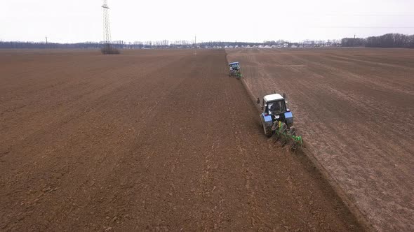 Agricultural Work in the Field, Two Blue Tractors Plow the Land