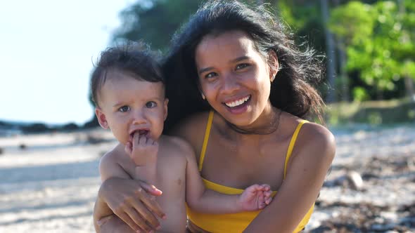 Joyful Lovely Young Mother and Adorable Little Baby Sitting Together Outdoor