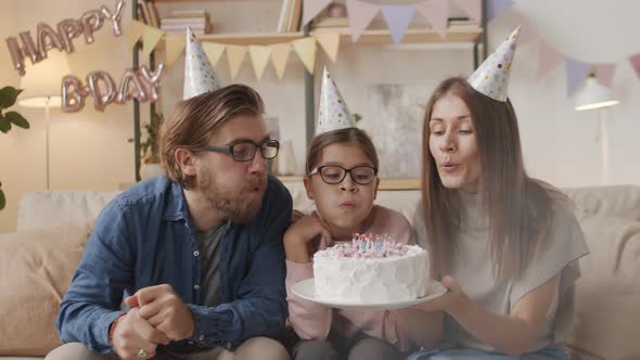Cheerful Young Family Blowing Out Candles alt