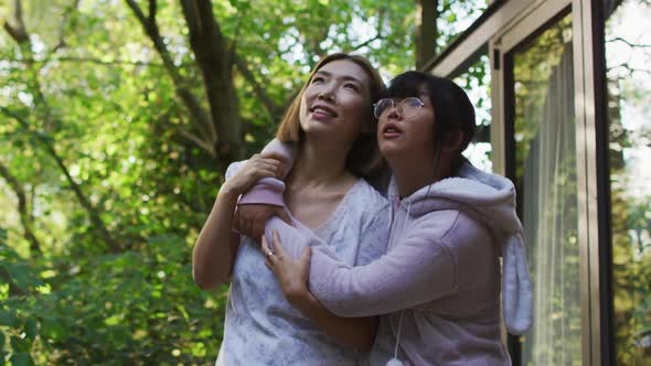 Asian mother and daughter embracing in garden and smiling alt
