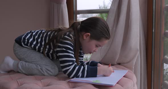 A Little Girl Drawing with Pencils at Home