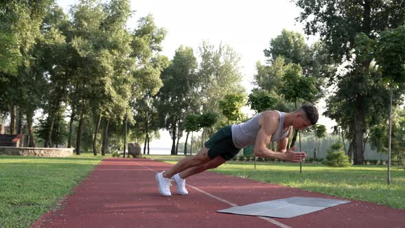 Man Showing Power Doing Pushups with Clapping on Fitness Mat in Park Strength alt
