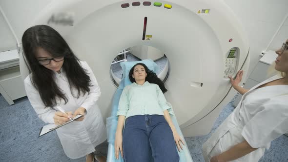 Female patient is undergoing CT or MRI scan under supervision of a radiologist alt