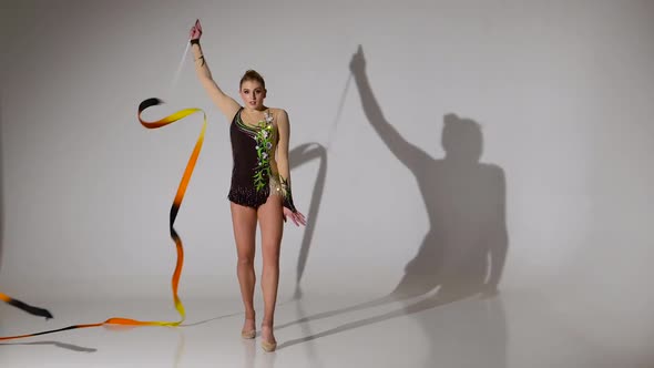 Rhythmic Gymnast Doing Acrobatic Moves with the Tape. White Background alt