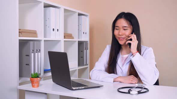 Cardiologist Consults By Phone in Office with White Interior alt