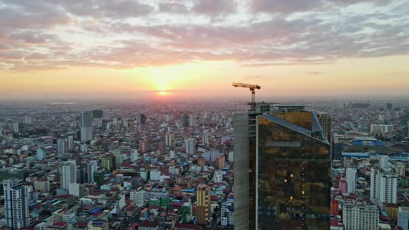 Golden Tower With Industrial Crane On Rooftop During Sunset In Phnom Penh, Cambodia. - aerial alt