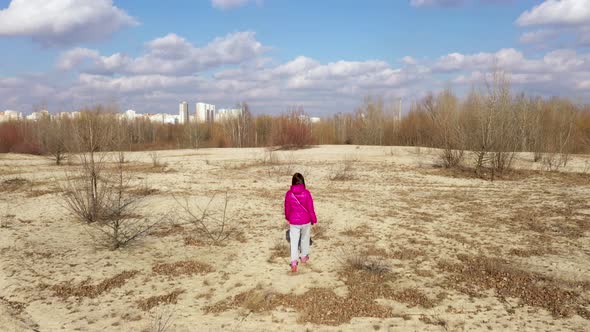 A Girl In a Bright Winter Jacket Walks On the Sand In a Forest Near the City