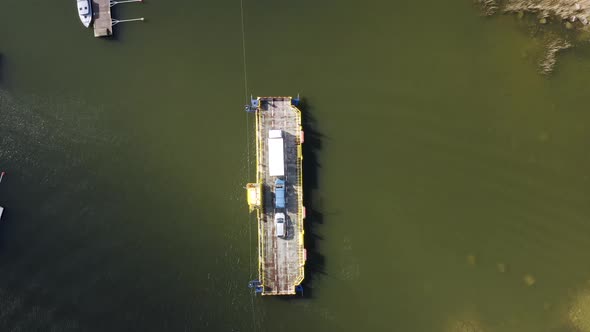 Aerial top down, drone shot of a cable ferry, arriving at a dock, in the archipelago of Porvoo, sunn alt