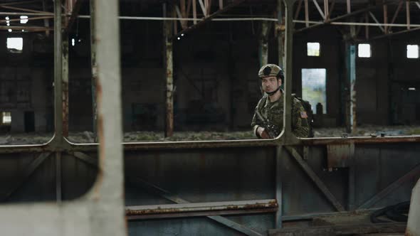 Military Man with Weapon Patrolling Destroyed Factory alt