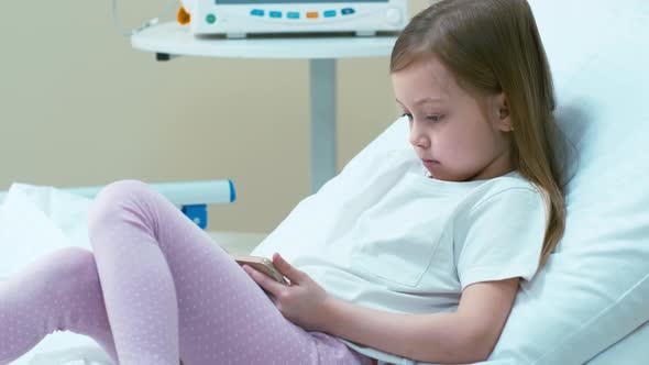 Girl laying on therapy bed and playing games on mobile telephone