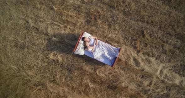 Young couple in love lies on bed in field with dry grass