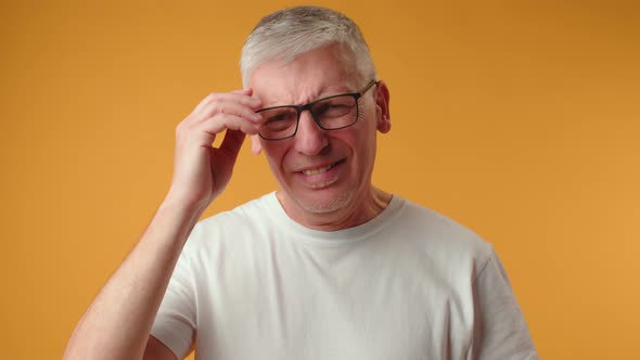 Sad Senior Man Starting to Cry Over Yellow Background