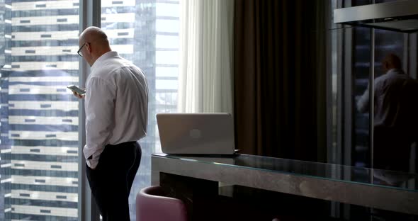 Bald Rich Man in Glasses and Business Clothes Decides Working Moments in the Morning in the Kitchen alt