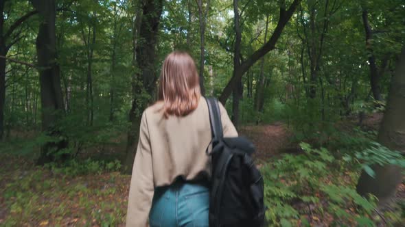 Girl with Backpack Walks in the Woods