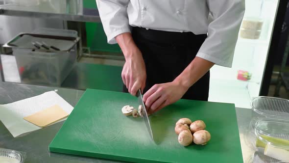 Slicing mushrooms with a steel knife on a green background.