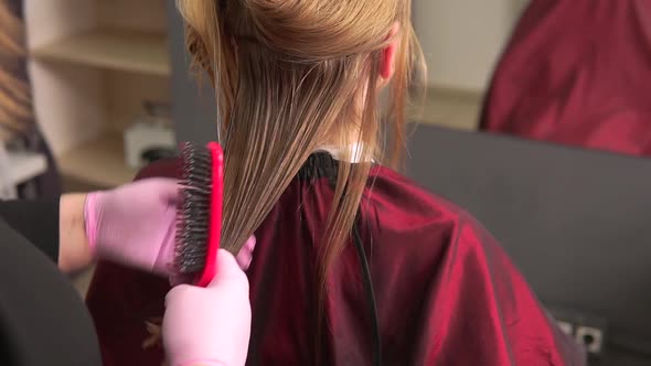 A Hairdresser in Pink Latex Gloves Combs Her Dyed Blonde Hair