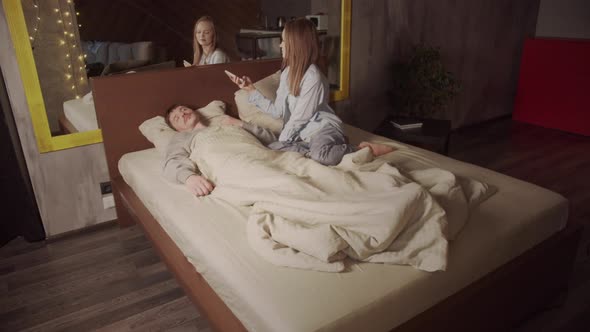 Young Wife Takes Photos Her Beloved Sleeping Husband Smartphone While Lying Bed alt