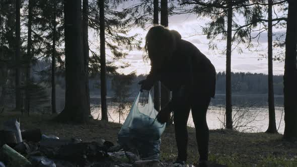 Young Woman Altruist Collecting Trash in the Forest