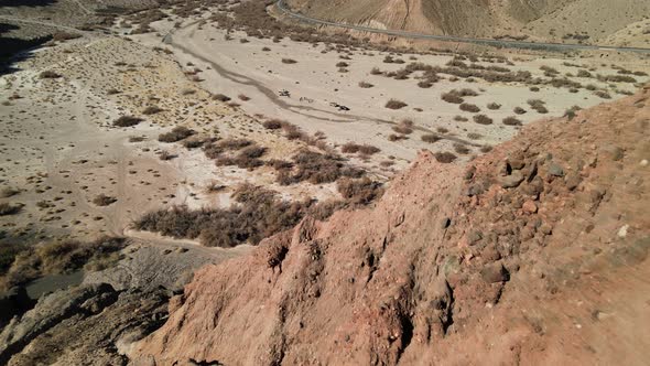 A drone flies backward over the rocky desert cliffs of Afton Canyon in the Mojave Desert of Californ alt