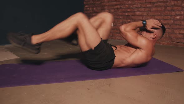 Young Man with a Naked Torso Training in the Room on a Sports Mat and Does an Exercise on the Press alt