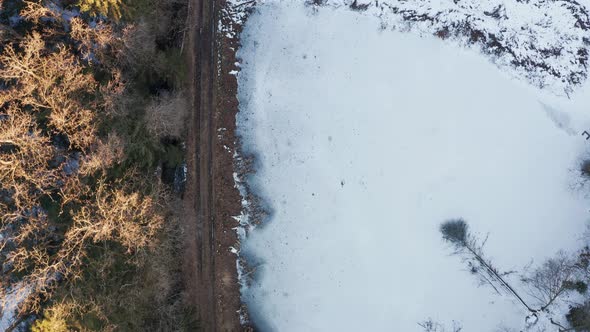 Aerial View at Frozen Lake in the Middle of Winter Forest