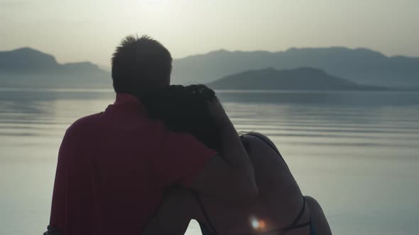Happy Couple in Love Sitting on the Beach By the Sea at Sunset alt