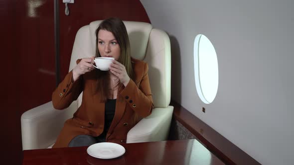 Woman in Airplane Cabin First Business Class Drinking Coffee alt