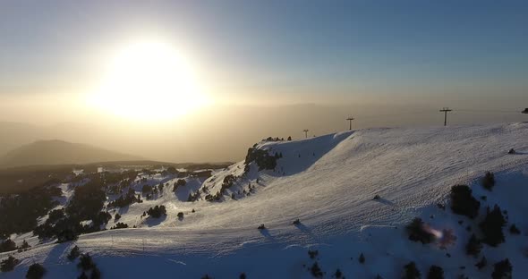 Snowmobiles on downhill run at Chamrousse ski resort in the French Alps during sunset, Aerial follow alt