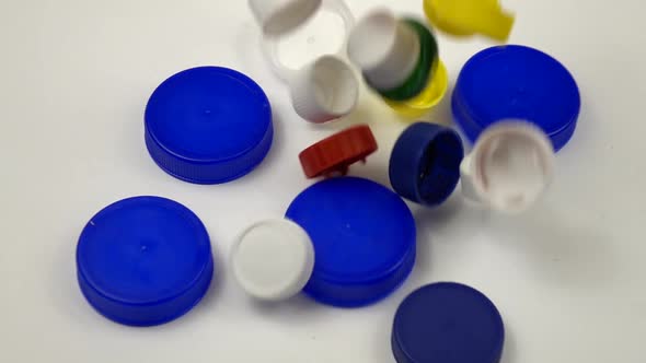 Small multi-colored bottle caps fall on the white table.