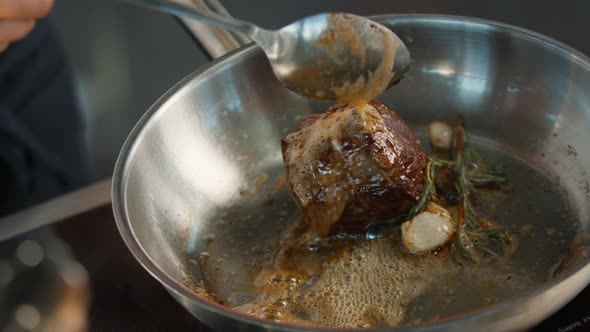 Close-up: Chef pouring sauce over filet mignon while cooking alt