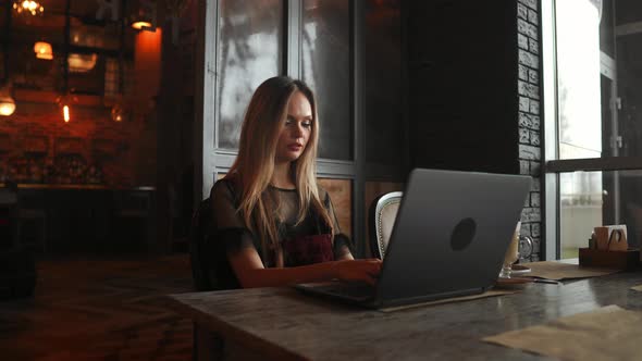 Happy Young Woman Drinking Coffee and Using Tablet Computer in Cafe alt
