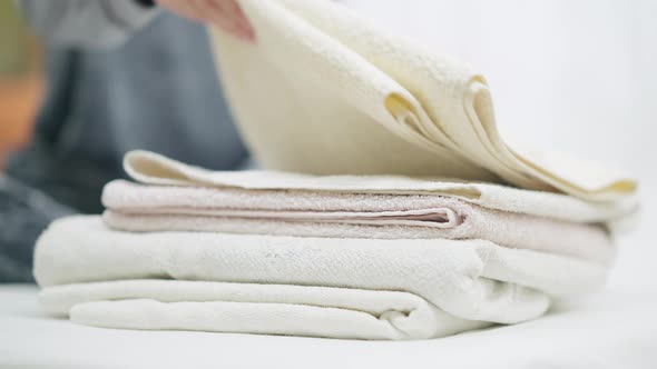 Female Hand Taking Clean Fresh Towel From Pile alt