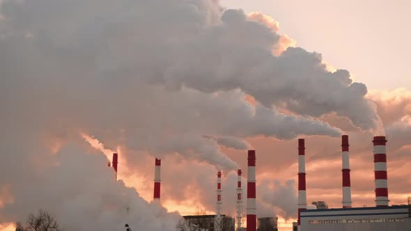 Huge Industrial Pipes at Sunset That Emit Lot of White Smoke alt