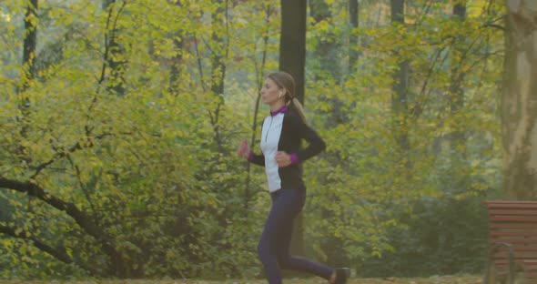 Fitness Girl Runs in the Morning Light in the City Park. alt