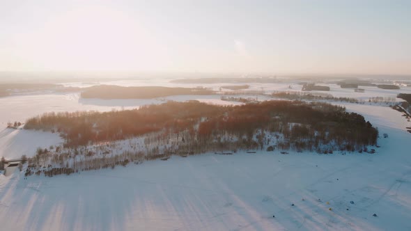 Aerial View of Frozen Lake and Forest on Sunny Frosty Day alt