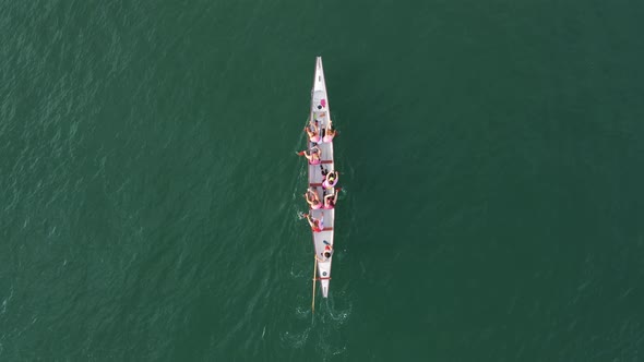 Aerial drone bird's eye view video of sport canoe operated by team of young clear waters. alt