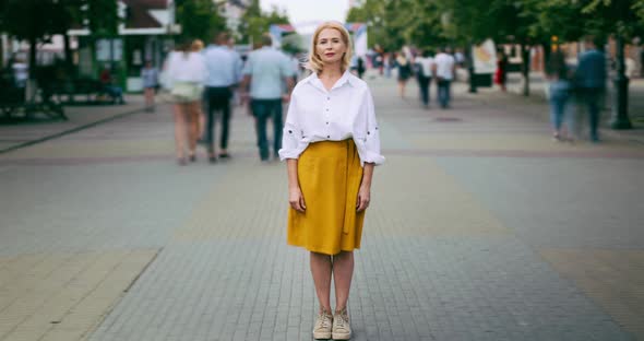 Time Lapse of Mature Woman Standing in City in Busy Street Looking at Camera alt