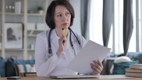 Pensive Old Lady Doctor Reading Medical Report for Treatment alt