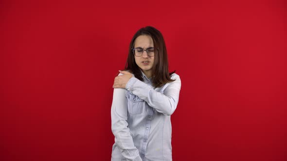 A Young Woman in Glasses Has a Sore Shoulder and She Touches It with Her Hand alt