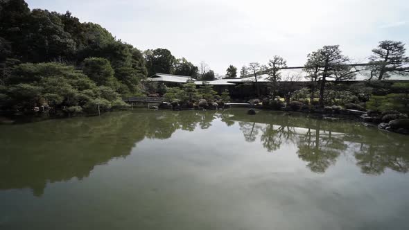 Pan left to right of a very quiet and still Japanese  pond with reflection of  a zen garden in the m alt