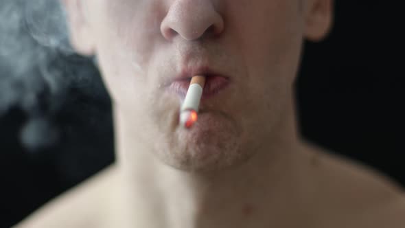 Caucasian Man Smoking a Cigarette on a Black Background