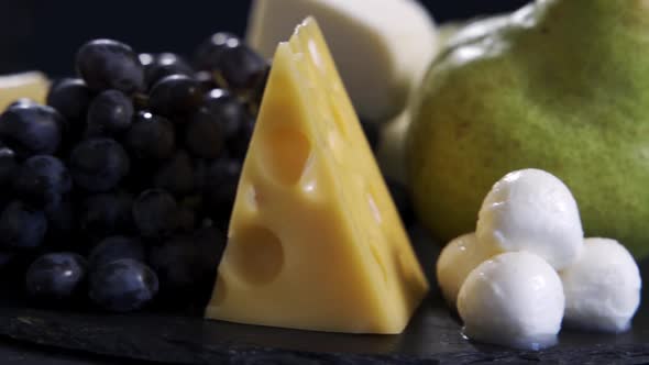 Various Types of Cheese Including Mozzarella Lie Next to Pears Grapes and Walnuts