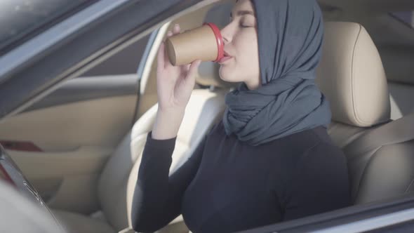 Portrait of Independent Smiling Young Muslim Woman Sitting in Car , Drinking Coffee and Talking By alt