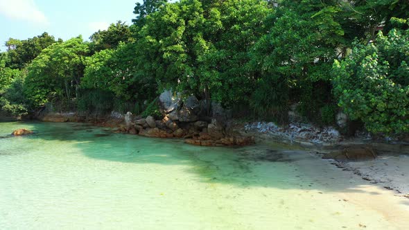Exotic beach under shadow of tropical trees and lush vegetation, clear calm water of lagoon washing alt