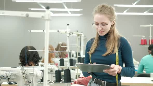 Portrait of fashion designer woman standing in a sewing shop. alt