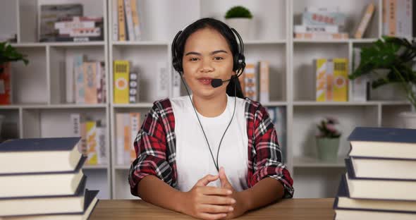 Happy female student in headphones and glasses talking at camera alt